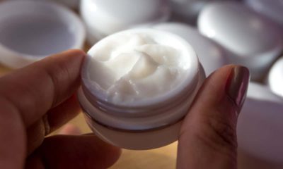 Photo of a small bottle of cream held between a thumb and a finger