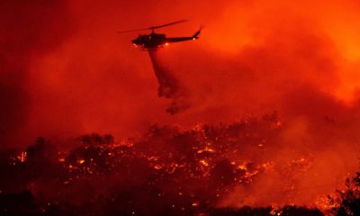 Photo of a helicopter dropping water on the Cave Fire