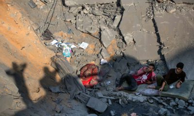 Photo of Palestinians sitting amid rubble