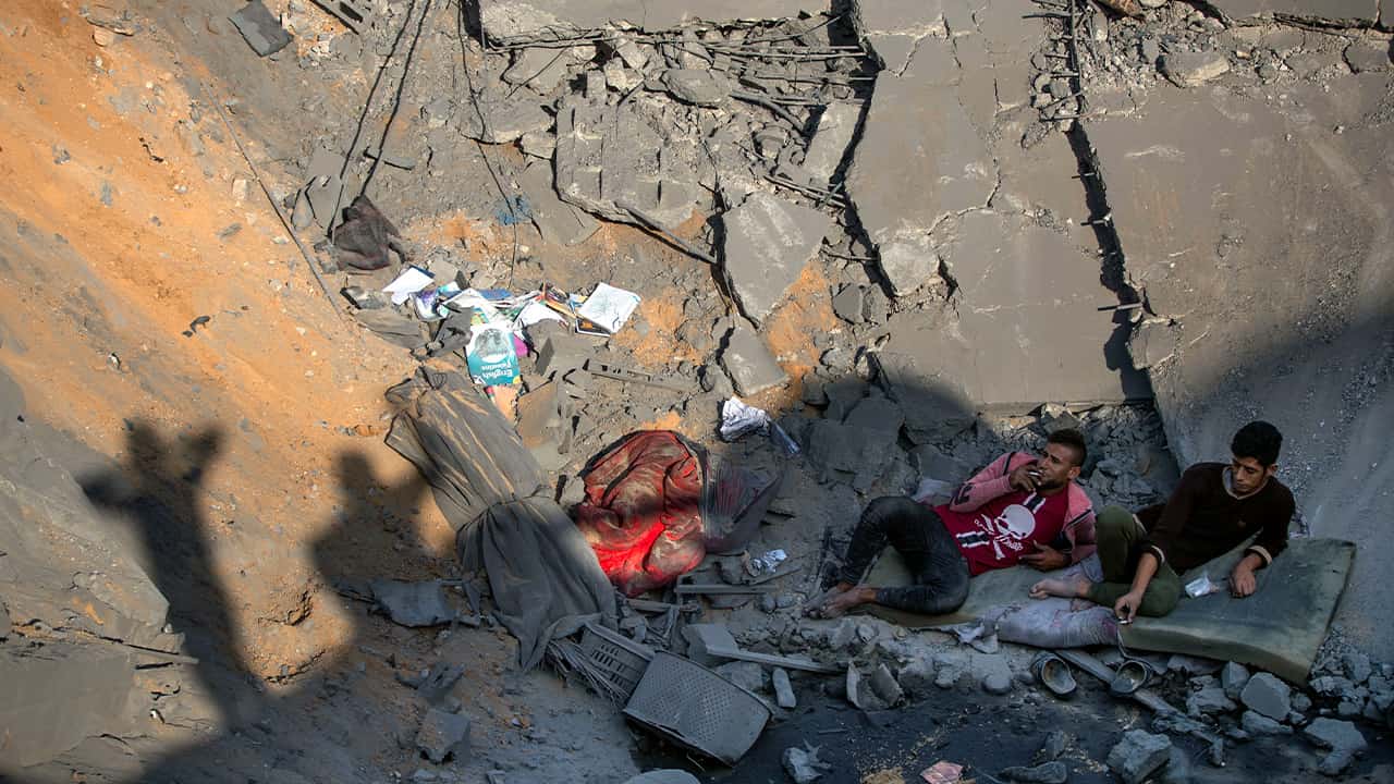 Photo of Palestinians sitting amid rubble