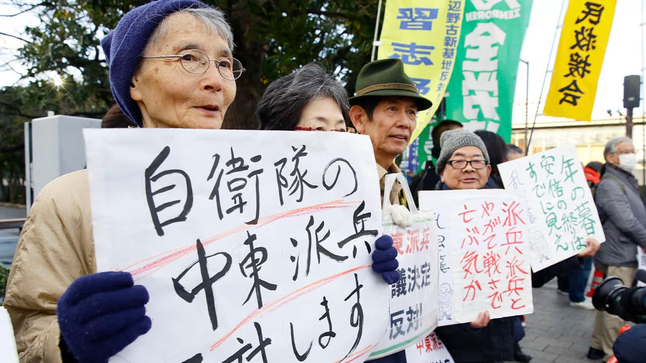 Photo of people holding placards protesting a troop dispatch tp the Middle East