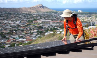 Photo of Dane Hew Len, lead installer for RevoluSun, placing a solar panel on a roof