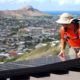 Photo of Dane Hew Len, lead installer for RevoluSun, placing a solar panel on a roof