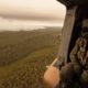 Photo of a Royal Australian Navy MRH-90 helicopter crew member looks out over fires burning near Cann River, Australia