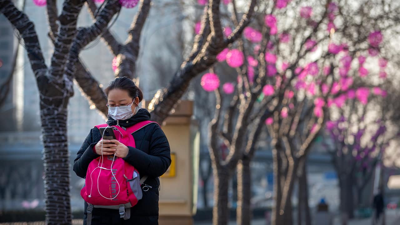 Photo of a woman wearing a face mask as she walks in Beijing