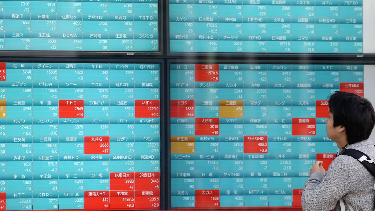 Photo of a man looking at an electronic stock board of a securities firm in Tokyo