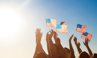 Photo of a blue sky and people holding American flags