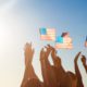 Photo of a blue sky and people holding American flags