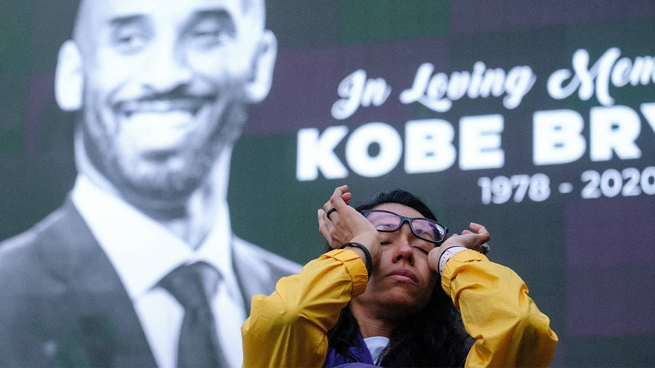 Photo of a woman wiping tears from her eyes at a Kobe Bryant memorial at the Staples Center in Los Angeles