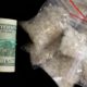 Photo of a roll of money and dime bags of meth