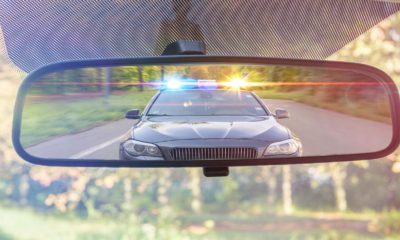 Photo of a cop car seen through a rear-view mirror