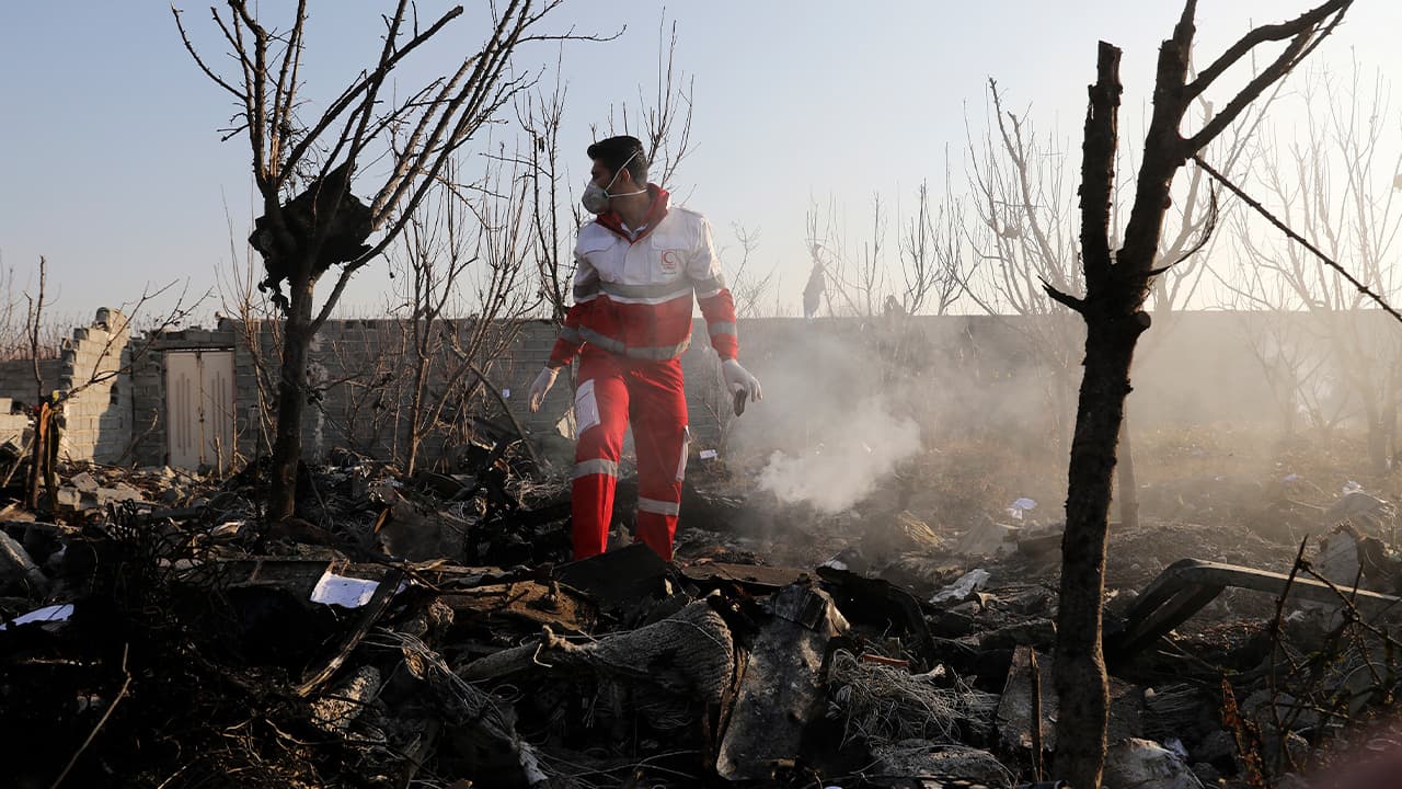 Photo of a rescue worker searching the scene where a Ukrainian plan crashed