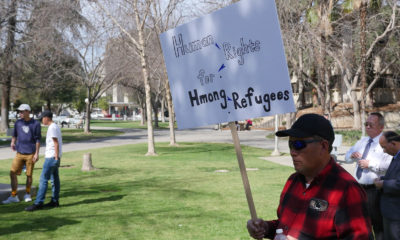 Photo of a man holding a sign at a Hmong rally