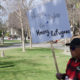Photo of a man holding a sign at a Hmong rally