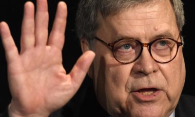 Photo of Attorney General William Barr putting his hand up