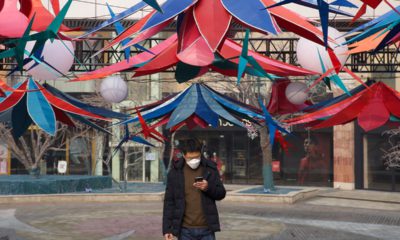 Photo of a man using his phone as he walks in Beijing, China