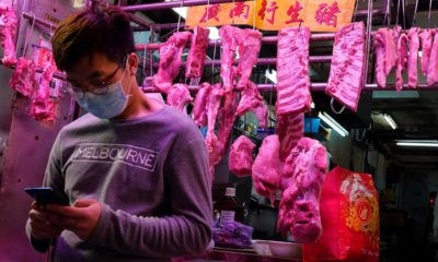 Photo of a man wearing a face mask in front of a meat booth in Hong Kong