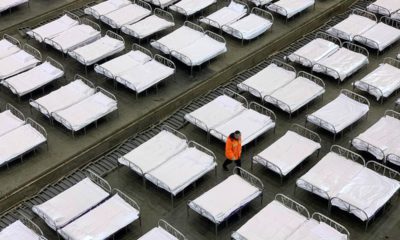 Photo of workers arranging beds in a convention center