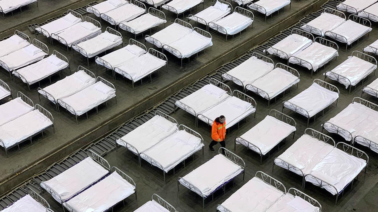 Photo of workers arranging beds in a convention center