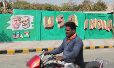 Photo of a man riding past a wall with portraits of U.S. President Donald Trump and Indian Prime Minister Narendra Modi