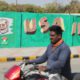 Photo of a man riding past a wall with portraits of U.S. President Donald Trump and Indian Prime Minister Narendra Modi