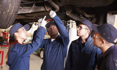 Photo of people in a shop class looking at a car