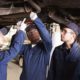 Photo of people in a shop class looking at a car