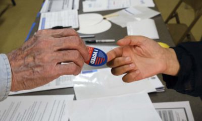 Photo of someone being handed an "I Voted" sticker