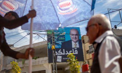 Photo of Israeli Arabs in a coffee shop near an election campaign poster showing Israeli Politician Ahmad Tibi of the Joint List in Tira, Israel