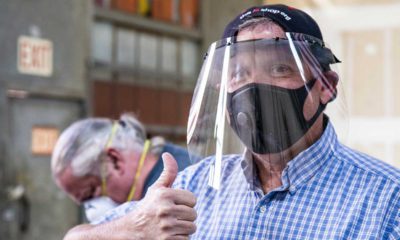 Photo of a man wearing a face shield that he made giving the thumbs-up sign