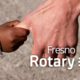 Composite of a man grabbing a child's hand with the Fresno Rotary logo po