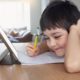 Image of a young smiling student doing online work on his tablet during COVID-19 lockdown