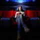 Photo of a woman who is the only one at a movie theateritting in