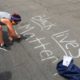 Photo of a protester writing "Black Lives Matter" in chalk on a downtown street in Fresno, California.