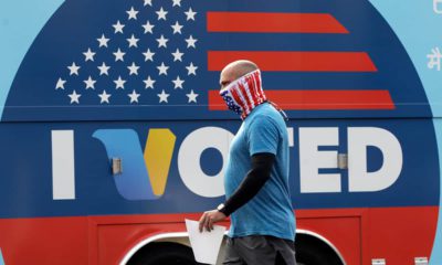 Photo of a man walking past an I Voted sign