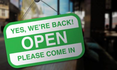 Photo of a sign on a business door welcoming customers back