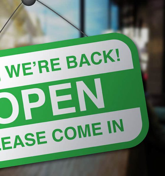 Photo of a sign on a business door welcoming customers back