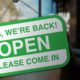 Photo of a sign on a business door welcoming customers back