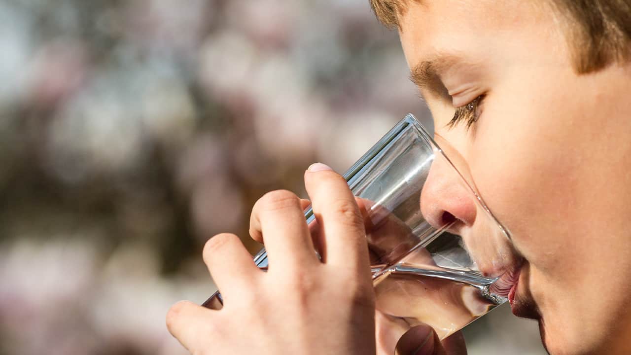 photo of a young man drinking a glass of water