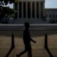 Photo fo a man walking past the Supreme Court