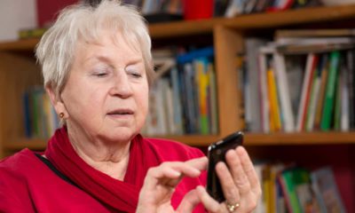 Image of a woman dialing a smartphone in a room filled with books