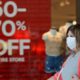 Photo of a woman walking past a store