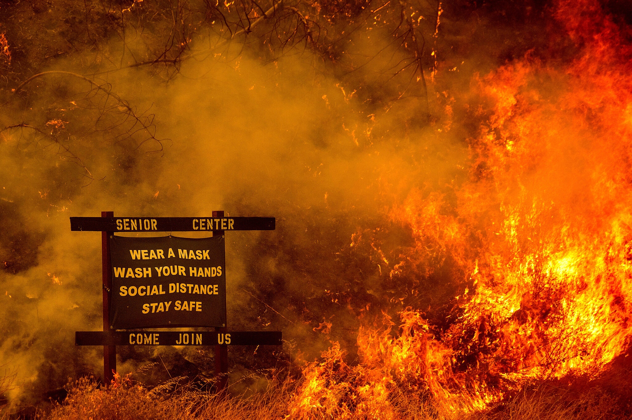 Photo of a sign for a senior center surrounded by wildfire flames