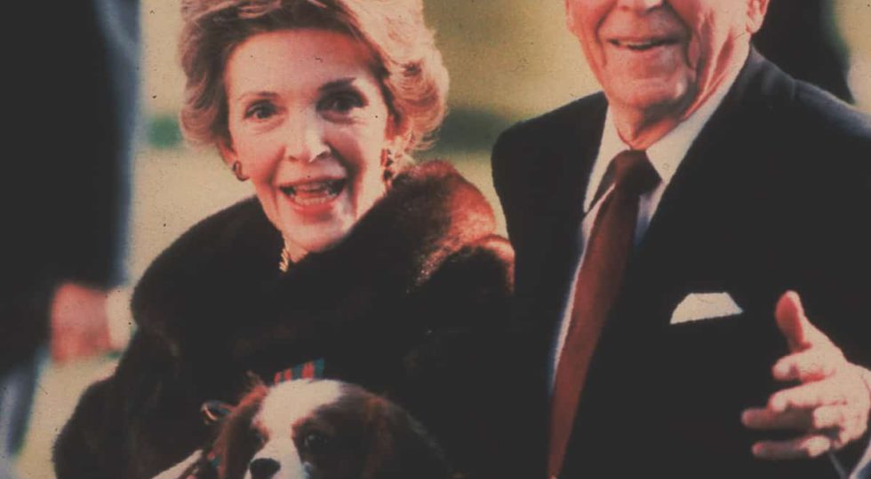 FILE – This December 1986, file photo shows first lady Nancy Reagan holding the Reagans’ pet Rex, a King Charles spaniel, as she and President Reagan walk on the White House South lawn. (AP Photo/Dennis Cook, File)